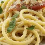 A creamy plate of pasta made with Boursin cheese, garnished with herbs and fresh vegetables.