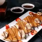 A stack of eggless pancakes with a drizzle of maple syrup and fresh fruit, showcasing a simple, egg-free breakfast